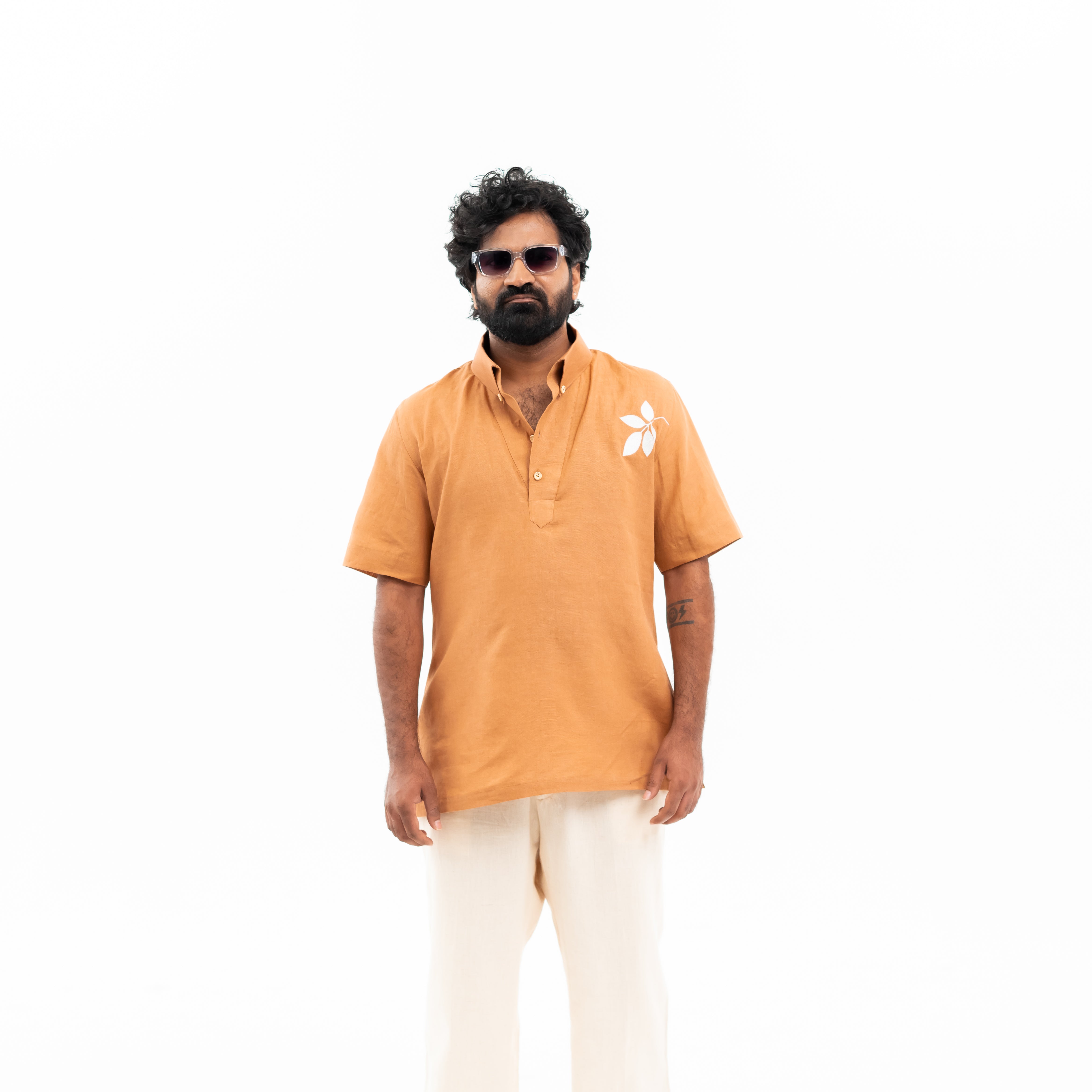 Man wearing an orange shirt and white pants on a white background