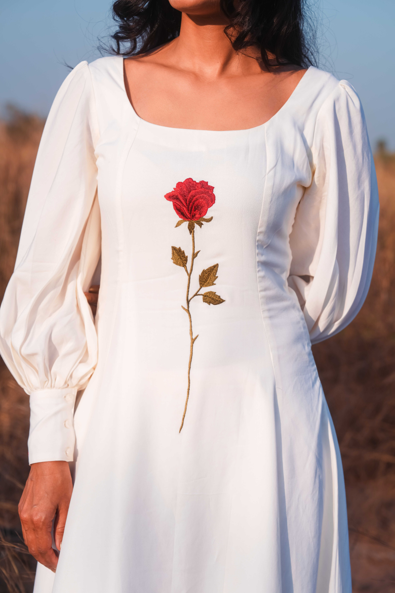 white dress with a red rose embroidered on it