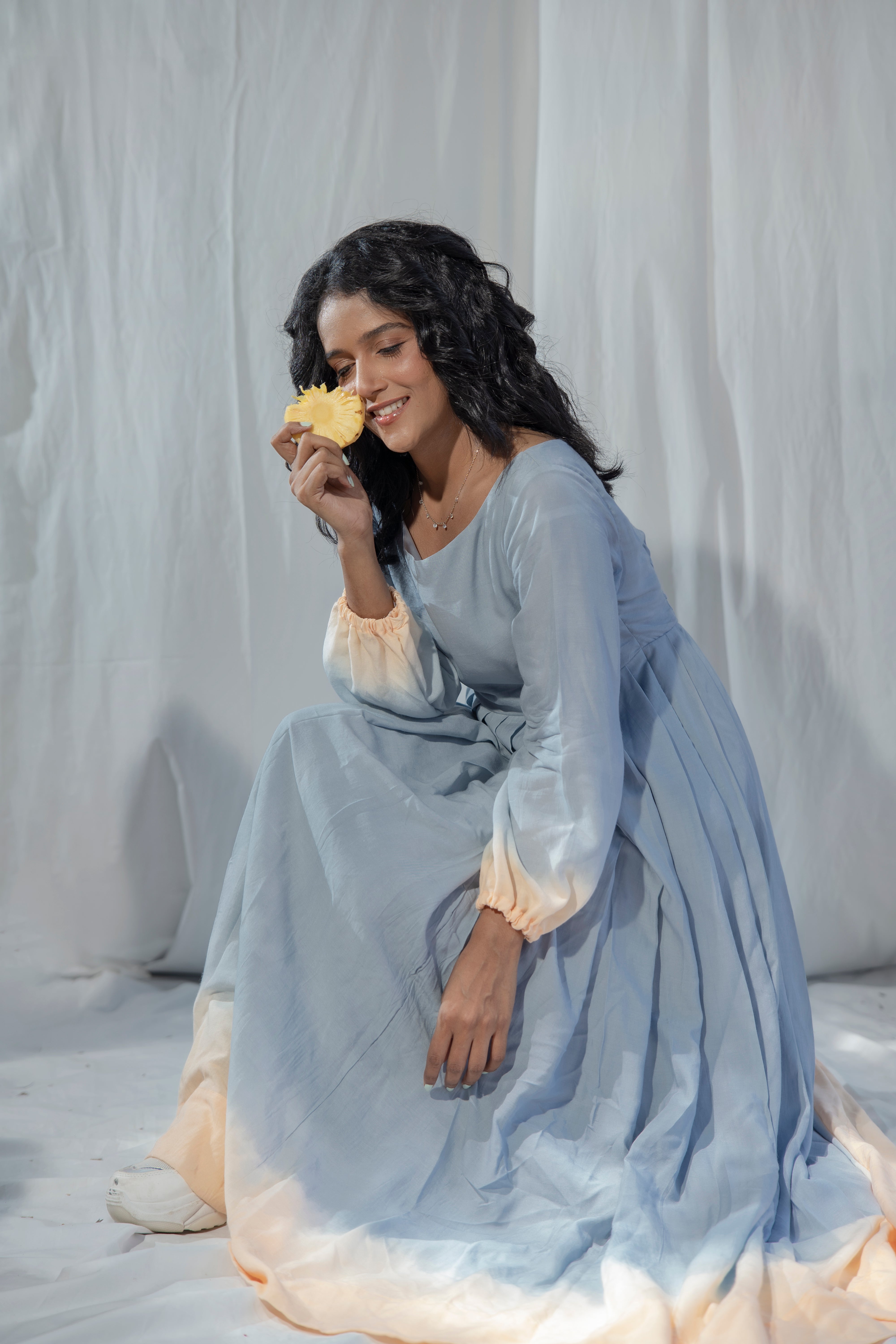 Woman in a light blue dress holding a yellow flower