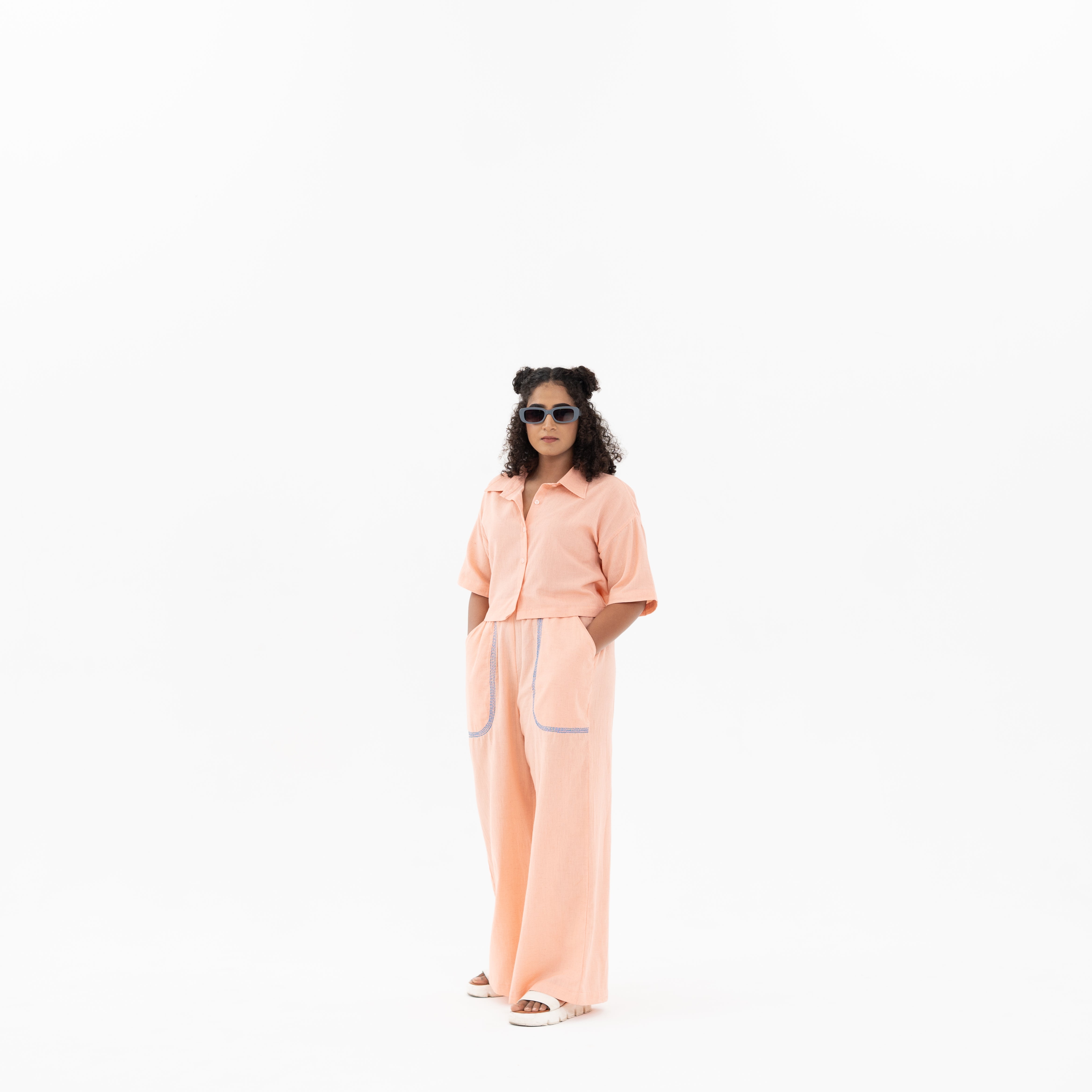 Person wearing a peach outfit on a white background